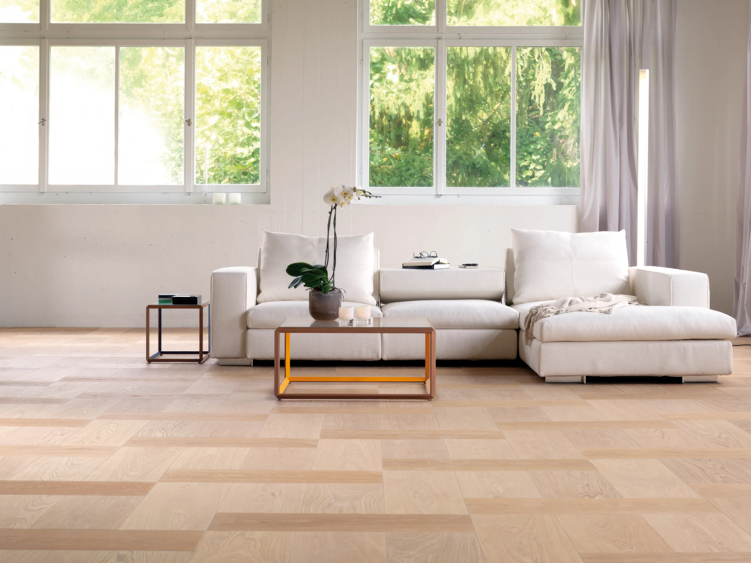 Houten vloer Bauwerk Formpark Oak Avorio in licht eiken, brede planken bij een witte bank.