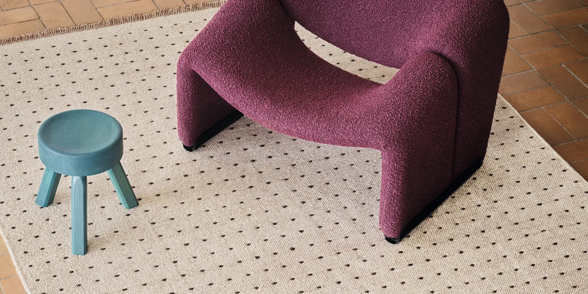 Kvadrat Yield Dot vloerkleed in naturel met stippen en franjes, bij een paarse fauteuil.