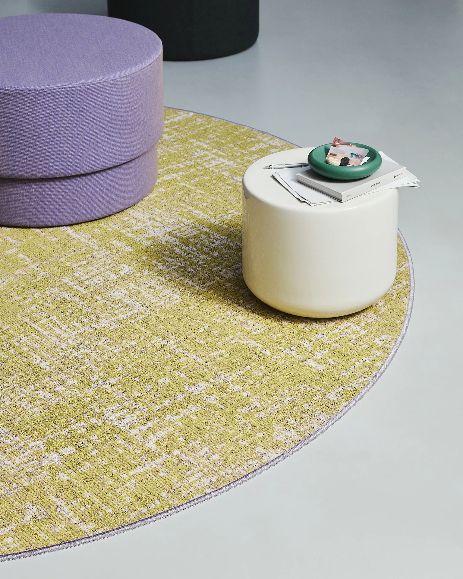 Ege ReForm Memory rond vloerkleed in Yellow Joy, geelgroen gemêleerd, met lila poef.