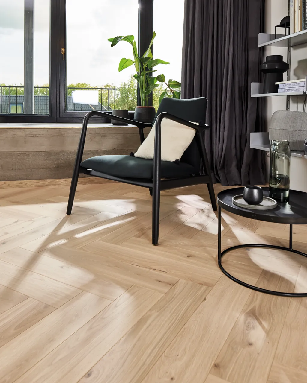 Boen Herringbone Oak, licht eiken visgraat parket bij een zwarte stoel.
