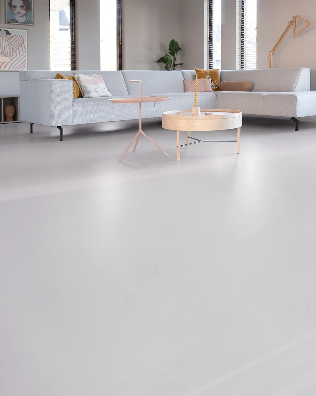 Arturo PU gietvloer in crème betonlook, naadloos in een woonkamer met grijze bank.