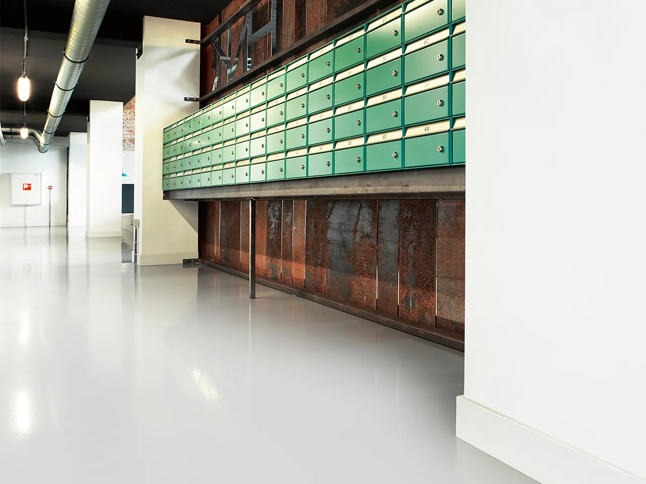 Arturo Epoxy gietvloer in hoogglans wit in een bedrijfshal met groene postvakken.