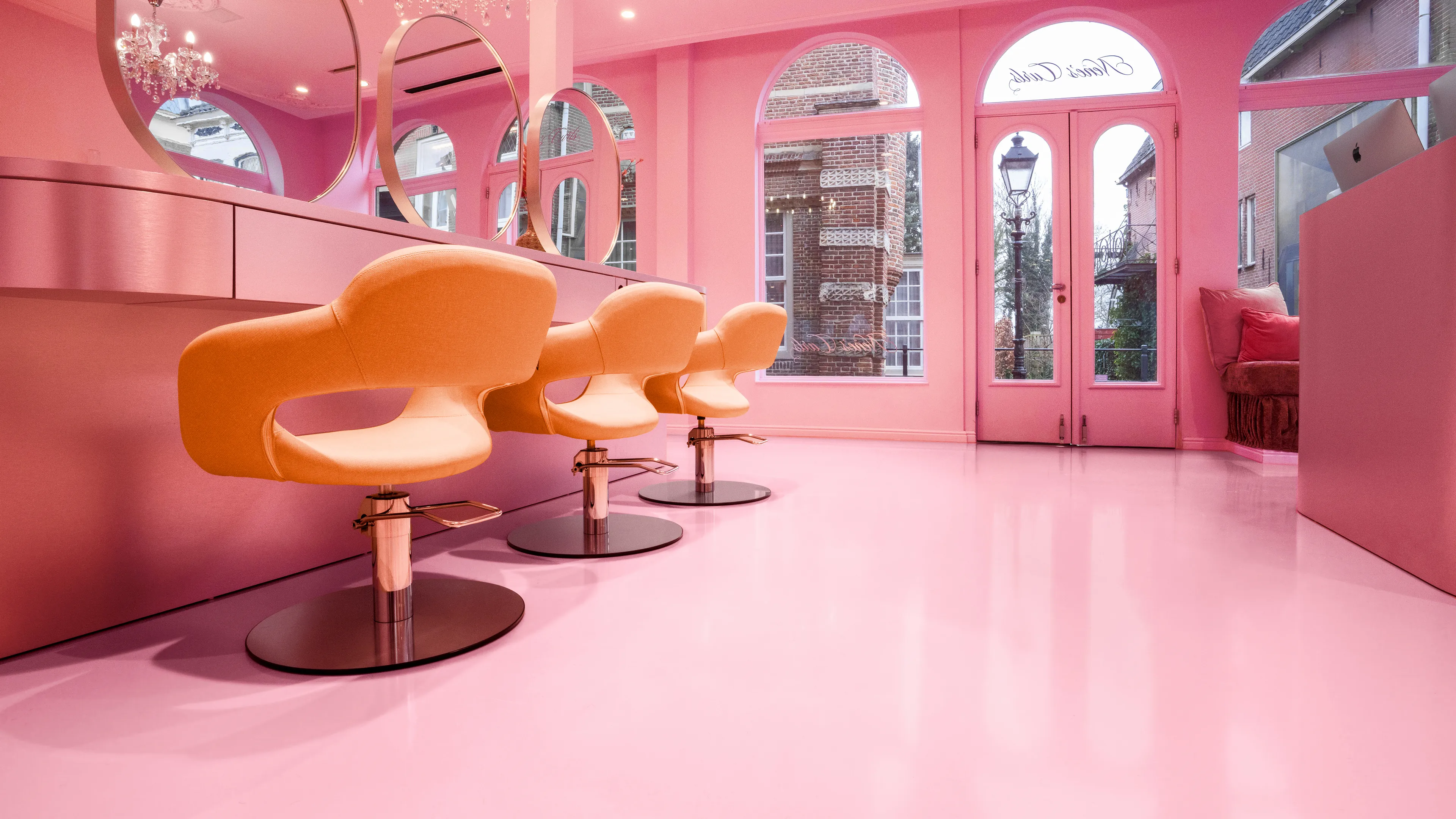 Arturo Epoxy gietvloer in hoogglans roze in een kapsalon met ronde spiegels.