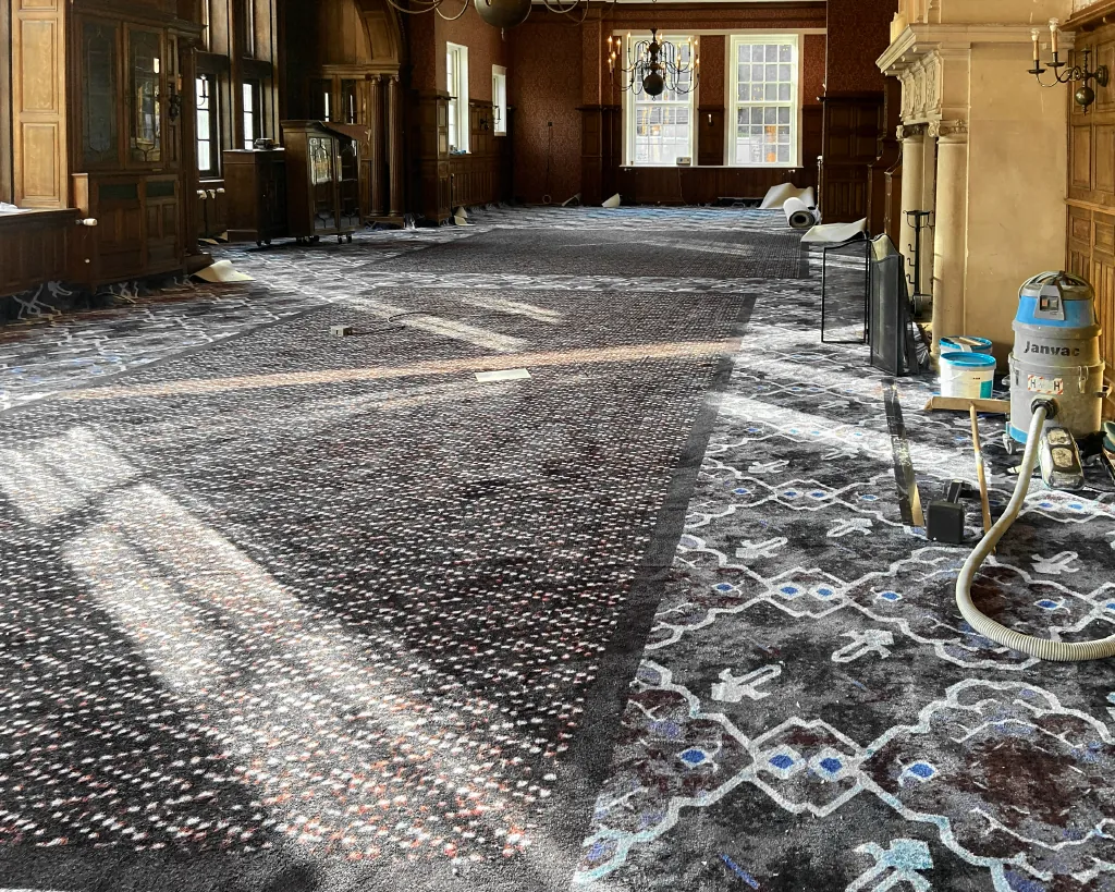 Leoxx kamerbreed patroontapijt tijdens montage in een monumentale zaal met schouw.