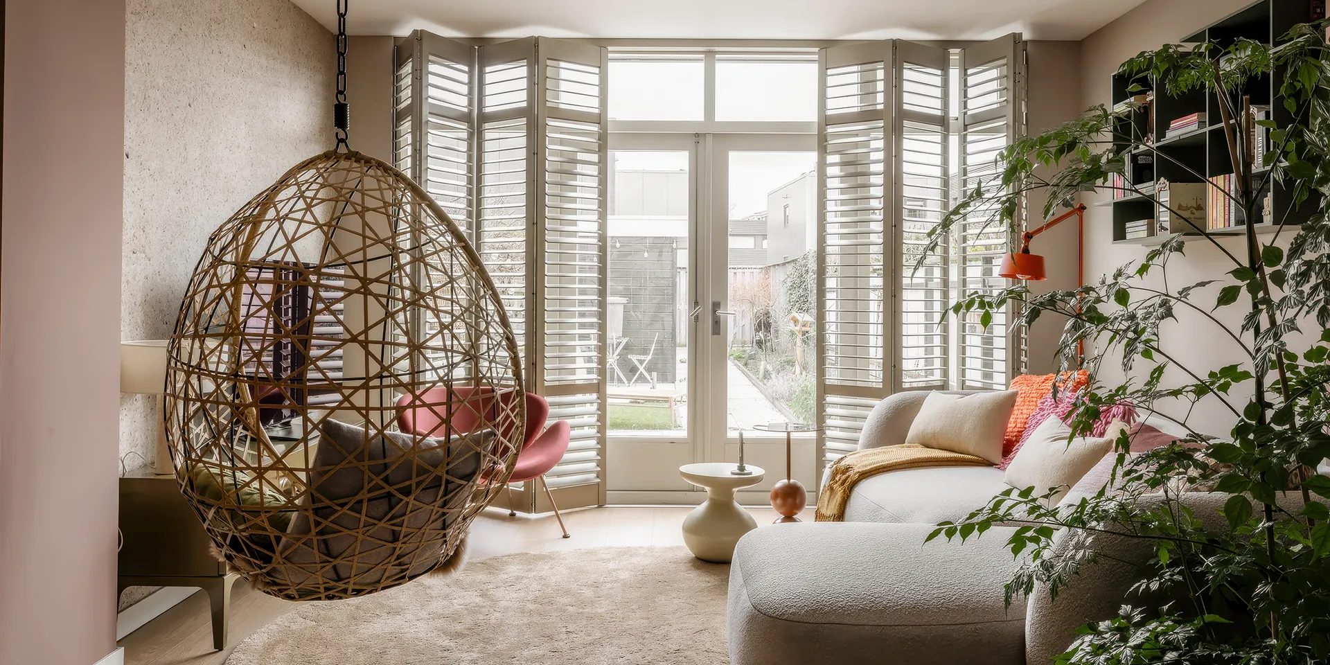 JASNO shutters in Old White rond tuindeuren, gevouwen panelen in een woonkamer.