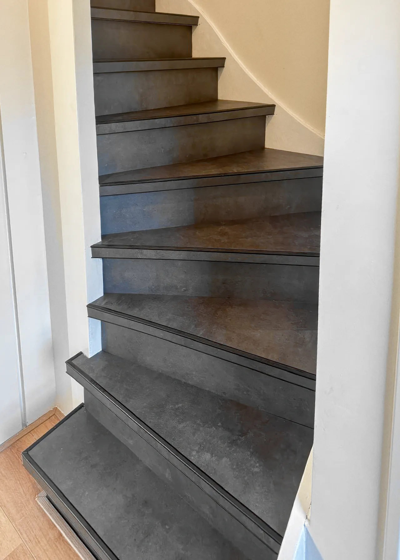 Ambiant Ceramo traprenovatie met PVC trap bekleed in antraciet betonlook en zwarte profielen.