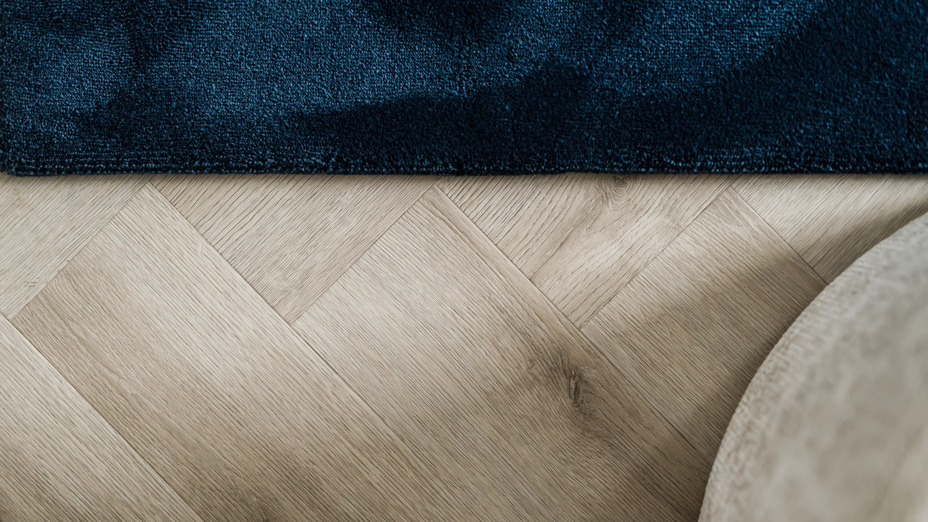 Therdex PVC vloer in visgraat met lichte eiken-look naast een diepblauw vloerkleed.