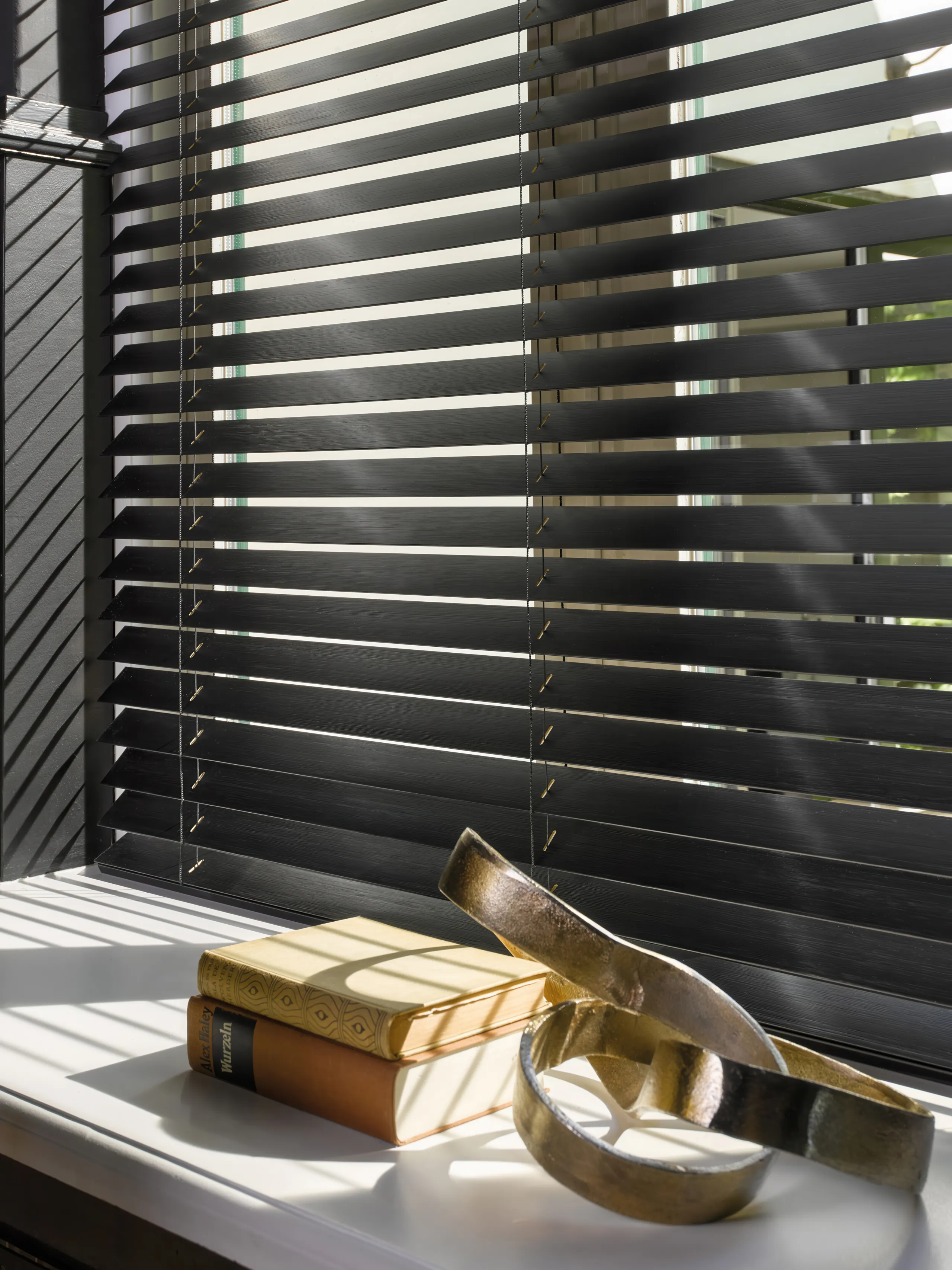 Luxaflex® houten jaloezieën in zwart, vrijhangend gemonteerd voor het raam.